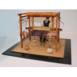 A model of a figure at a tartan loom, 18cm wide in Perspex case Condition report: Available upon