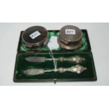 A lot comprising a cased pair of butter knives and two silver jewellery boxes, 6cm and 7cm diameter,