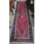 A red ground Persian runner with central medallion, matching spandrels and dark blue border 280cm