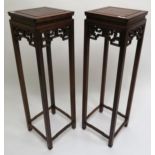 A pair of 20th century Chinese hardwood pedestal plant stands with stylized fretwork reliefs 123cm