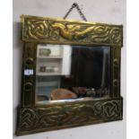 An early 20th century Arts and Crafts bevelled glass wall mirror with hammered brass framed