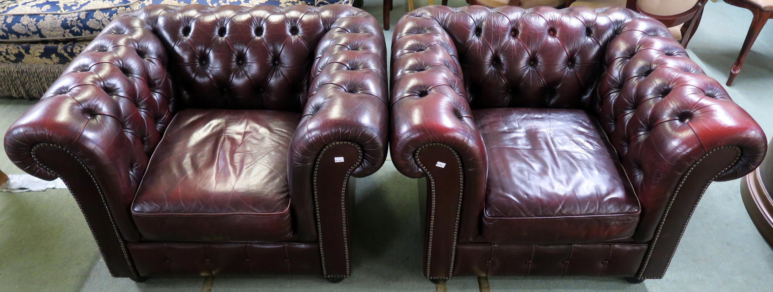A pair of contemporary oxblood leather upholstered chesterfield club chairs, 70cm high x 102cm