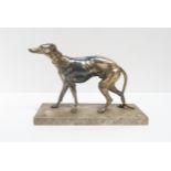 A white metal model of a greyhound modelled in a naturalistic pose on a rectangular hardstone base