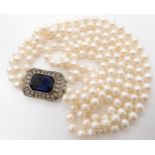 A three strand pearl necklace with a decorative continental silver diamante and blue gem set clasp