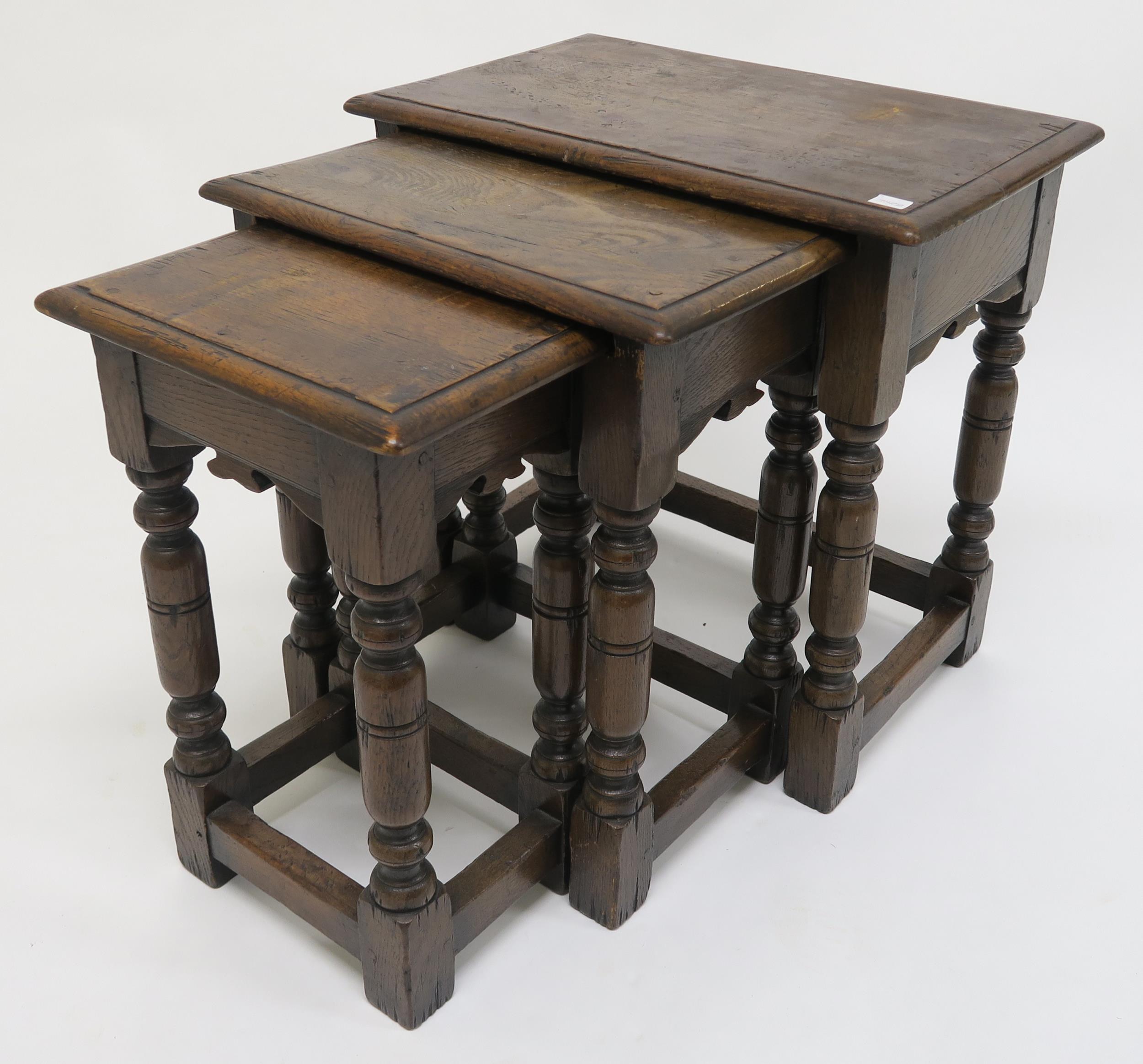 A 20th century stained oak nest of three tables on turned stretched supports, 50cm high x 51cm