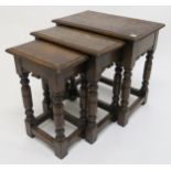 A 20th century stained oak nest of three tables on turned stretched supports, 50cm high x 51cm