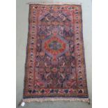 A dark blue ground hand knotted Hamadan rug with red central medallion and multicoloured border,