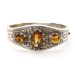 A white metal bangle set with citrines, with hand engraved decoration Condition Report:One citrine