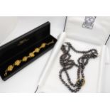 A gold plated Elizabeth Arden Bracelet and a string of black pearls Condition Report:Condition