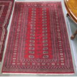 A red ground Bokhara style rug with all over lozenge design, 188cm long x 127cm wide Condition