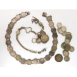 A silver three penny bit necklace, with further loose coins, and a white metal decorative