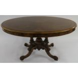 A VICTORIAN WALNUT OVAL TILT TOP BREAKFAST TABLE on turned columns above carved quadripartite base