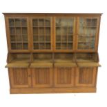 AN ARTS AND CRAFTS OAK BOOKCASE with four astragal glazed doors above four fall front writing slopes