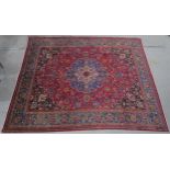 A RED GROUND PERSIAN HAND KNOTTED MASHAD RUG with cream and blue central medallion,matching blue