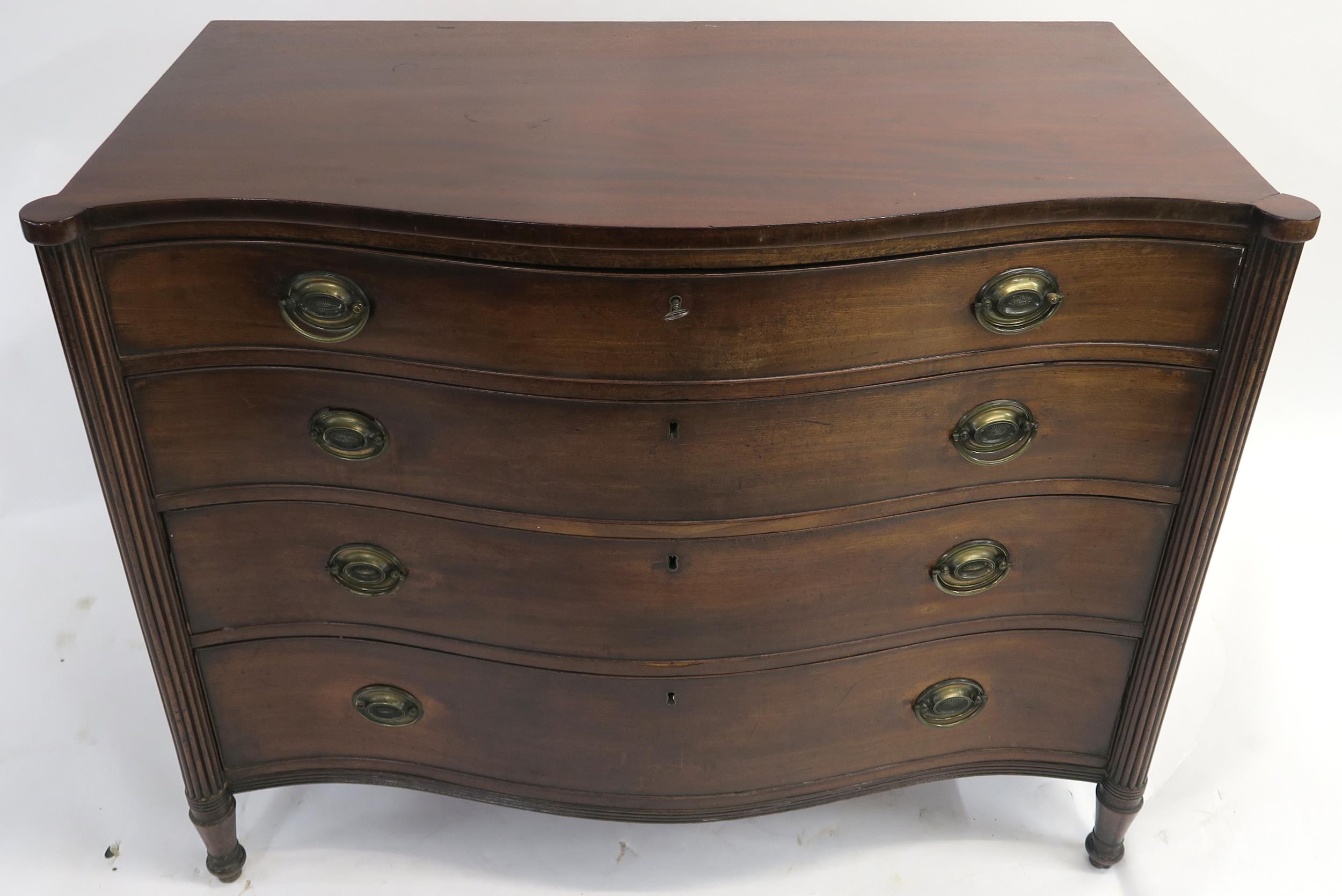 A 19TH CENTURY MAHOGANY SERPENTINE CHEST with four graduating drawers, flanked by fluted columns and