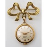 A LADIES 18K GOLD LIDHER FOB WATCH  with 18k gold bow brooch attached. The white dial with copper