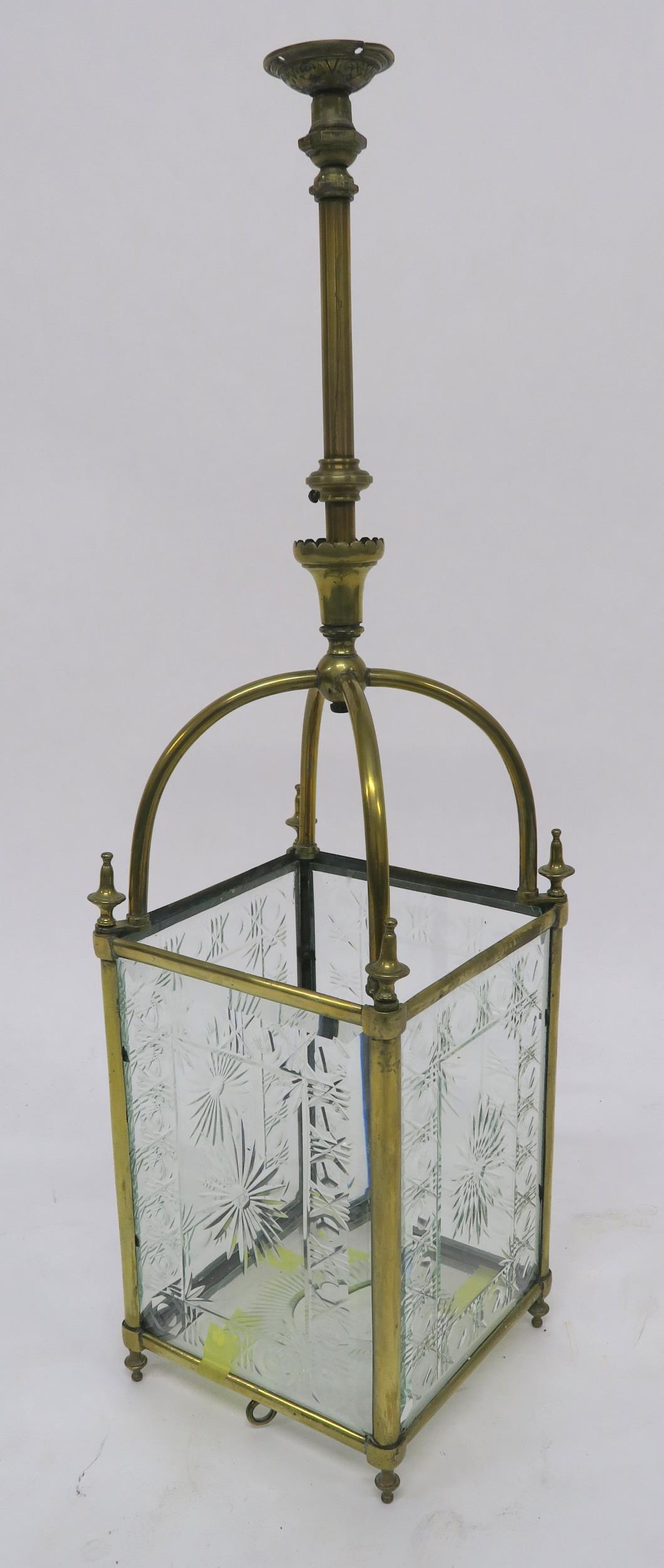 AN EDWARDIAN BRASS AND CUT GLASS HALL LANTERN set with four foliate cut panels and base, 90cm