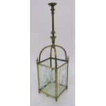 AN EDWARDIAN BRASS AND CUT GLASS HALL LANTERN set with four foliate cut panels and base, 90cm