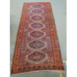 A TERRACOTTA GROUND BELOUCH RUG,  with seven geometric medallions