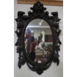 A Victorian oval wall mirror with extensively carved oak frame and an early 19th century mahogany