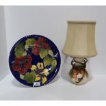 A Moorcroft Hibiscus pattern charger together with a similar pattern lamp in differing colourway