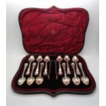 A set of twelve silver coffee spoons and sugar tongs with scrolling foliage borders and lobed bowls,