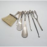 A silver handled shoe horn, another example, a silver handled brush, a silver handled button hook,