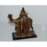 A cold-painted spelter table lighter, modelled as a Arab carpet seller with camel, 22cm high