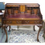 A reproduction mahogany writing desk with extensive upper compartments, the top inset with maroon