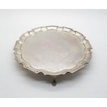 A silver salver with piecrust rim upon three hoof feet, London 1920, makers mark rubbed, 338 gms