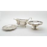 A silver sauce boat with scrolling handle upon three hoof feet, by J.W Benson Ltd, London 1938, a