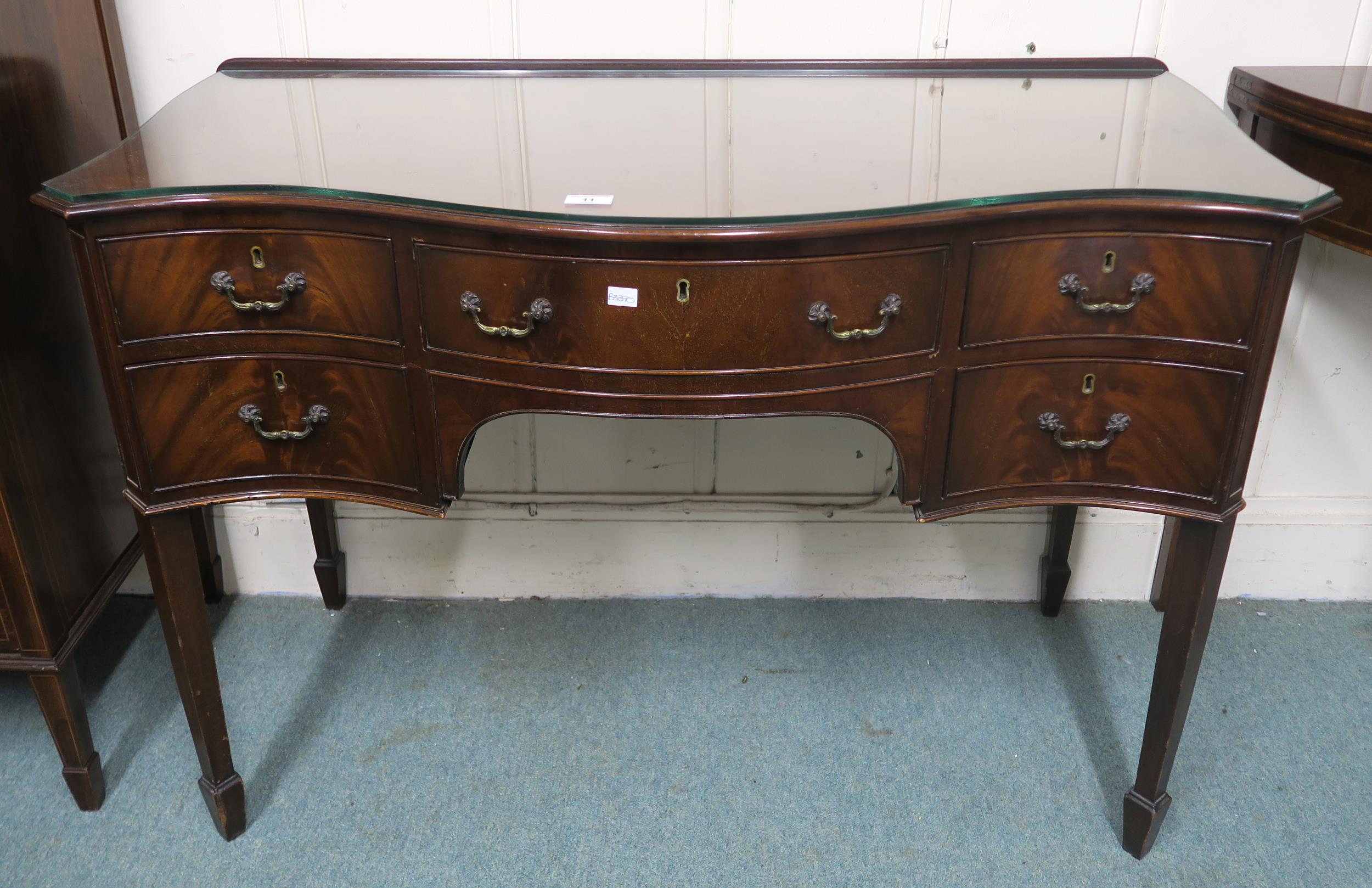 A 20th century mahogany serpentine front desk with single central drawer flanked by two drawers