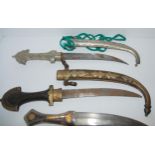 Three middle-eastern daggers in decorative scabbards, tribal dagger in leather scabbard and powder
