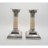 A pair of George V silver candlesticks, with gadrooned drip pans, modelled as Corinthian columns