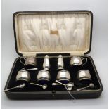 A George V eight piece silver condiment set, of octagonal form, with blue glass liners, by