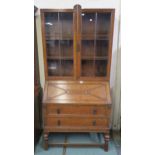 A 20th century oak bureau bookcase with glazed bookcase top above fall front two drawer writing