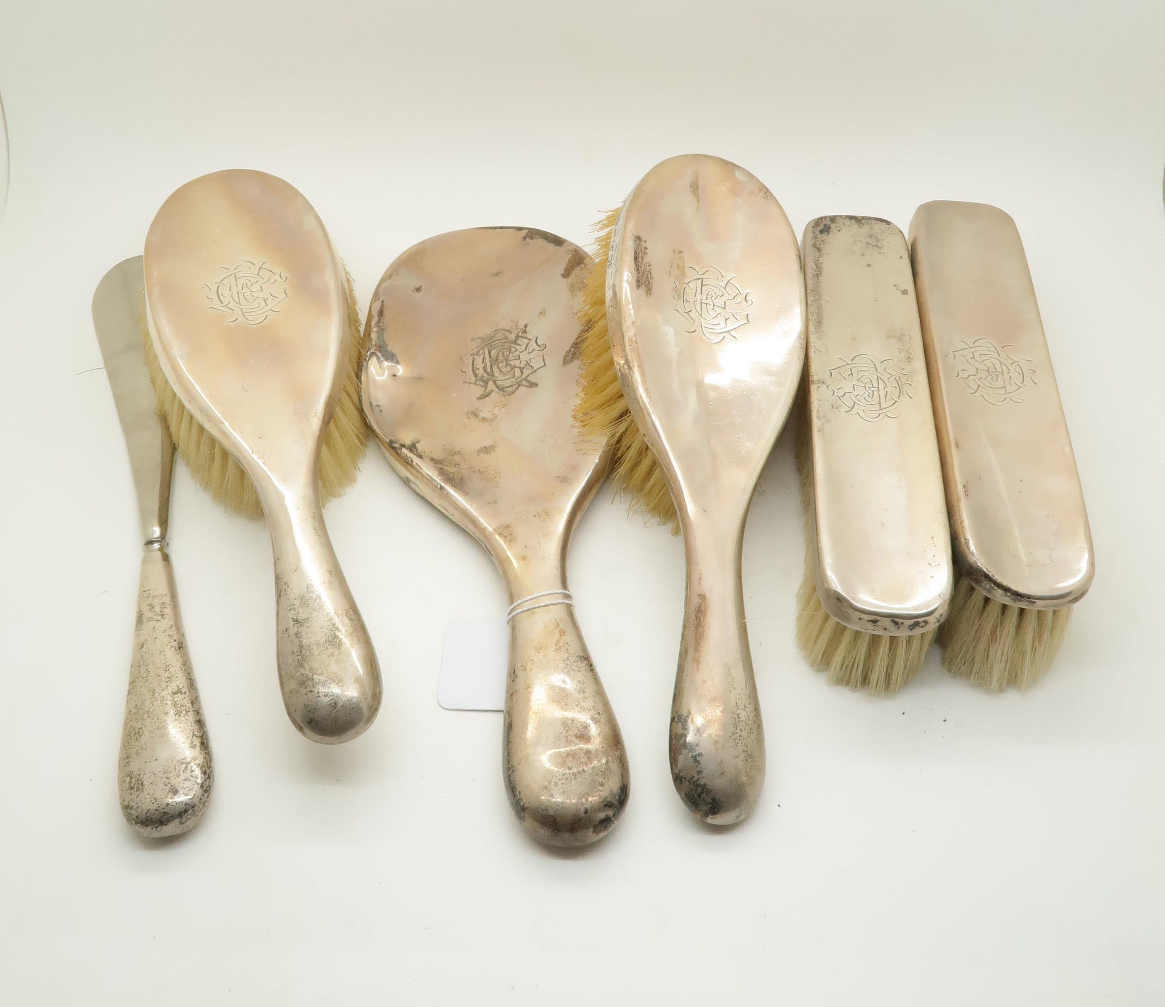 A six piece silver vanity set, comprising a hand mirror, two clothes brushes, two hair brushes,