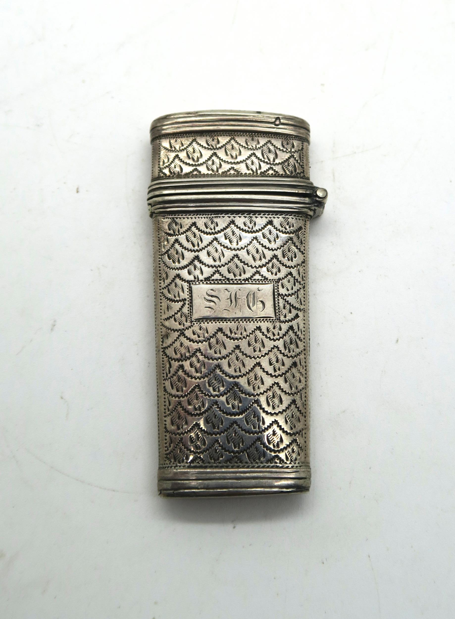 A silver etui, with bright engraved scale motif decoration surrounding an initialled rectangular