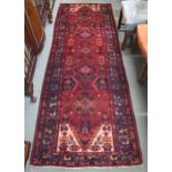 A red ground Iranian Hamedan runner with dark blue borders, 175cm long x 101cm wide Condition