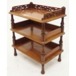 A late Victorian mahogany three tier what-not with turned uprights and a fretwork galleried top,