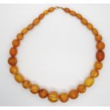 A string of amber coloured beads, largest bead approx 23mm diameter smallest 12.4mm x 8.7mm,