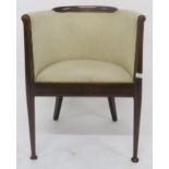 An early 20th century walnut framed art deco tub chair upholstered in cream upholstery on turned