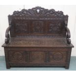 A 20th century carved oak hall settle with hinged seat, 104cm high x 115cm wide x 46cm deep