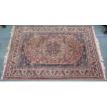 A modern pink ground eastern style rug with floral central medallion and dark blue spandrels,
