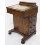 A Victorian walnut Davenport with hinged compartment above writing surface with four drawers to