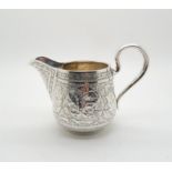 A Russian silver cream jug, with chased decoration of riders and animals within cartouches,