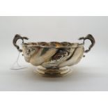 A late Victorian twin handled bowl, the wrythen body with repousse floral decoration, the handles