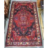 A red ground Hamadan rug with central medallion, dark spandrels and cream border, 188cm long x 109cm