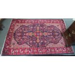 A dark blue ground Persian rug with red central medallion, cream spandrels and red floral borders,