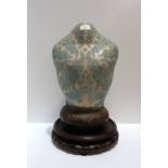 A ceramic bust with impressed blue floral decoration, with a modelled brown base, upon a hardwood